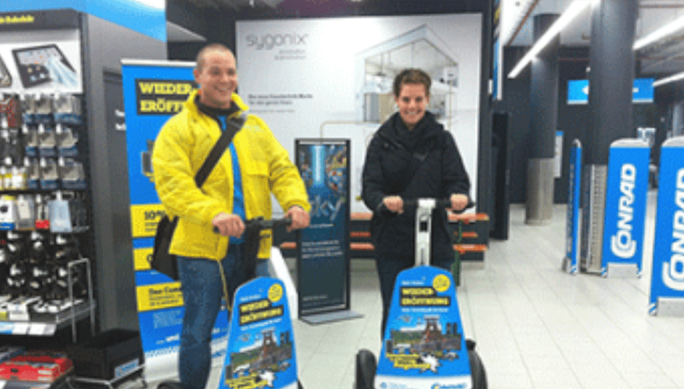 Lächelndes Paar auf Segways in einem Geschäft, ideal für Segway Promotion und Events, mit Fokus auf Sicherheit
